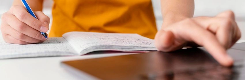 pessoa-escrevendo-em-um-caderno-e-utilizando-o-computador